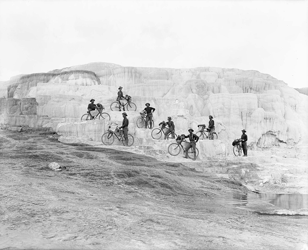 Soldiers of the 25th Infantry Bicycle Corps posing with their bicycles on the white travertine of Minerva Terrace in Yellowstone National Park, 1896